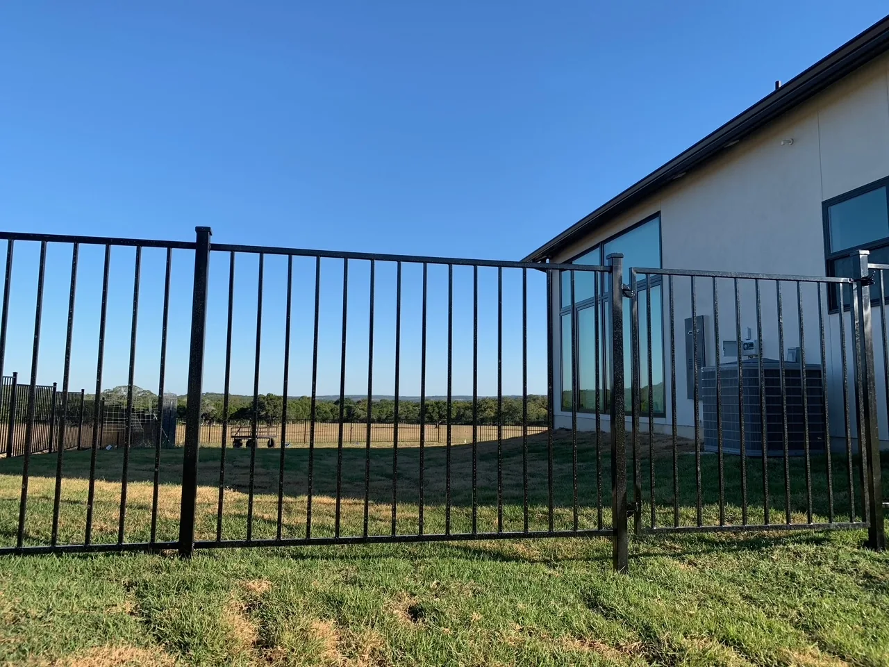 Black ornamental fence and pedestrian gate near stone steps